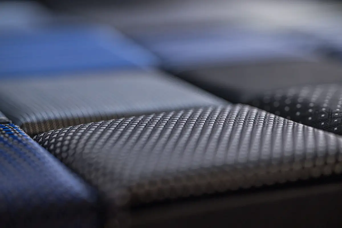 Close-up of a grey birdseye weave in a stack of open suiting swatches