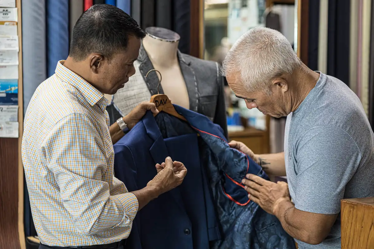 Professional suit fitting at New David Jone Fashion - master tailor Johnny adjusting custom suit jacket for client in Patong Phuket